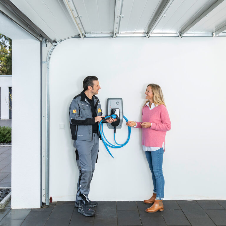 Installateur berät eine Kundin zur Handhabung einer Wallbox